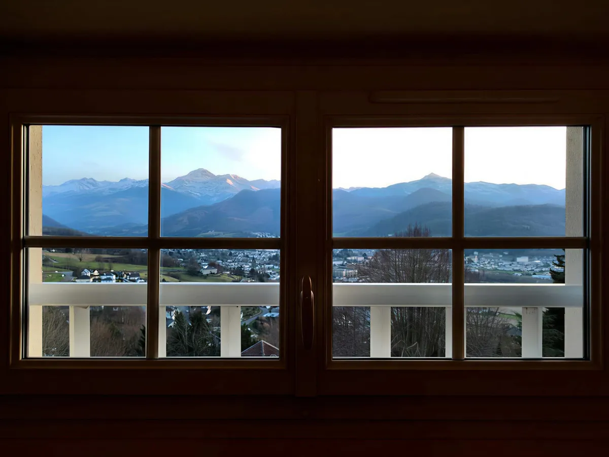 宽窗框住村庄屋顶与比利牛斯山峰
